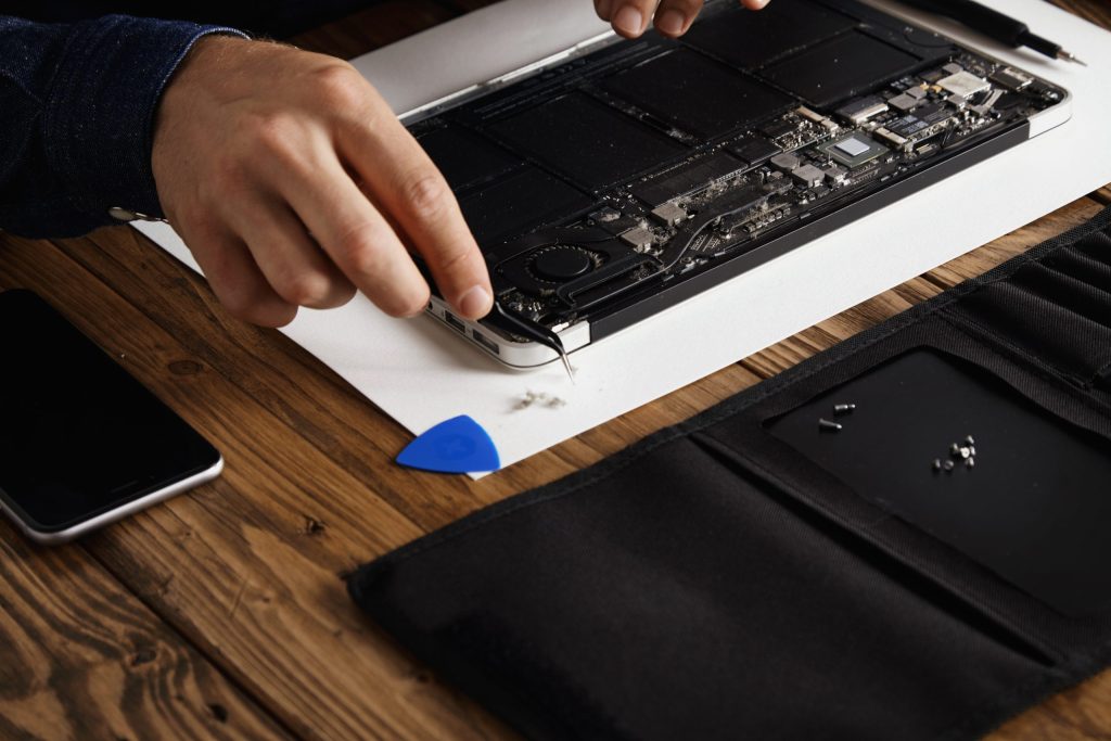 hand that uses angled esd tweezers remove dust from electronic boards broken slim computer laptop fix it make work again