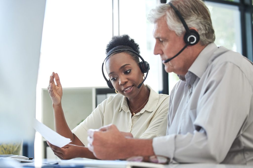 i dont understand how this works shot two call centre agents sitting together office having discussion