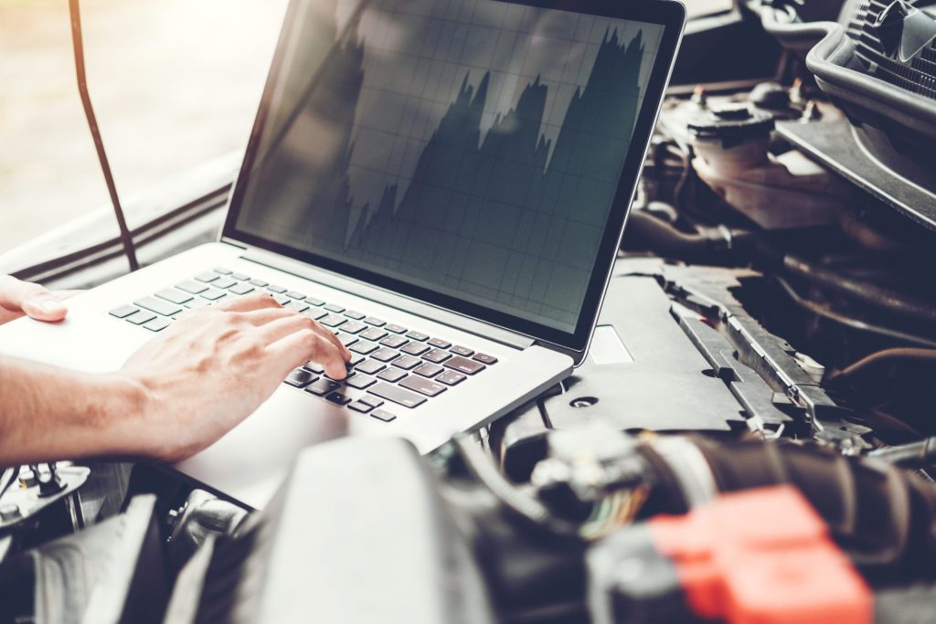 cropped hands mechanic using laptop while repairing car