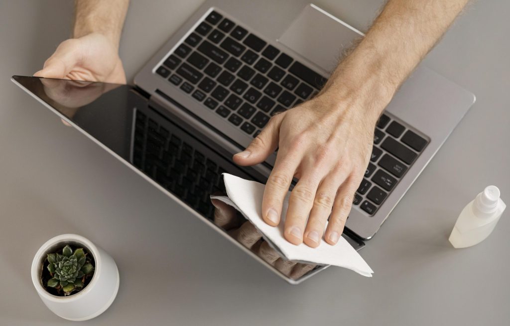 employee disinfecting electronic device